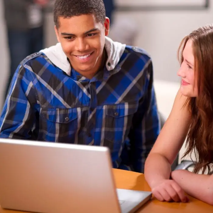 two students studying from a laptop