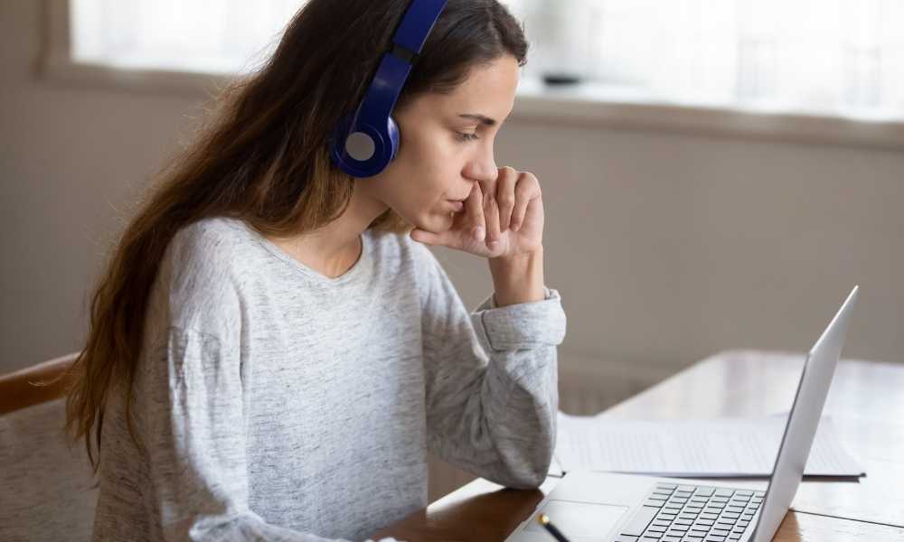 Woman studying with headphones by window